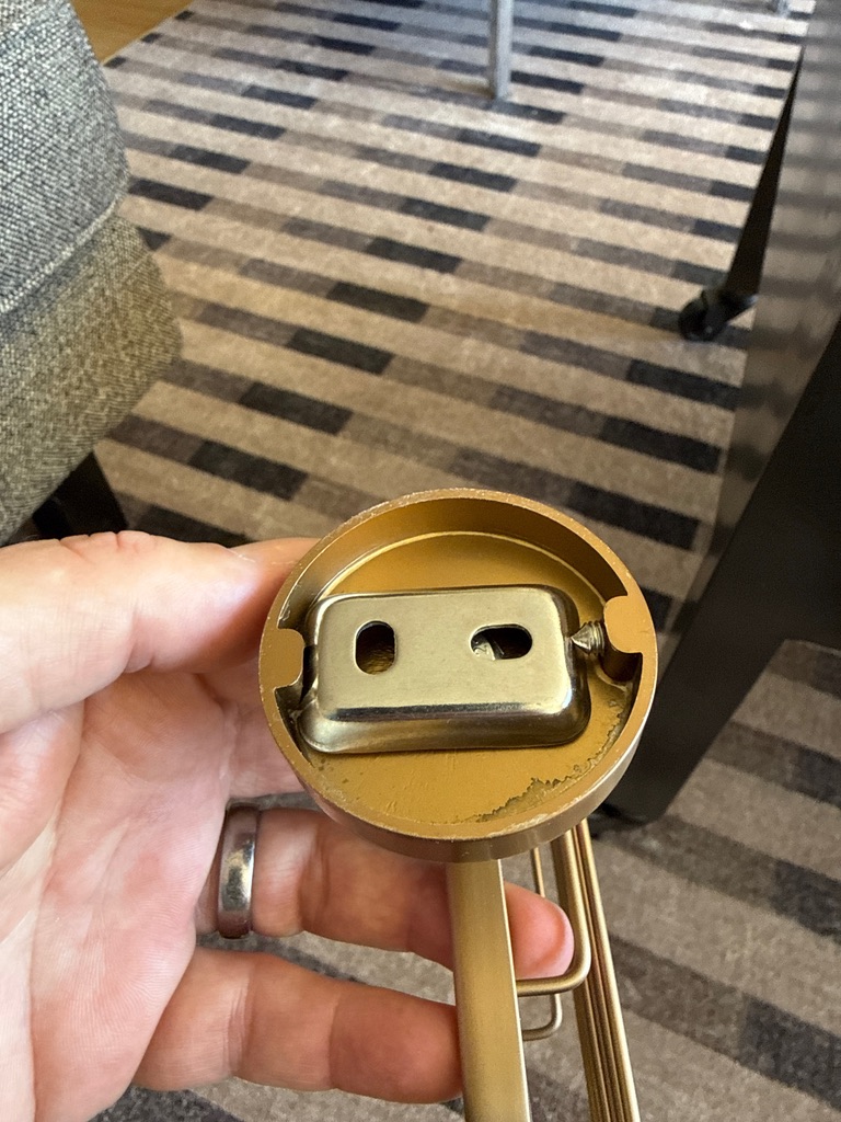 Backside of the brass escutcheon showing the keyhole mounting bracket and set screw