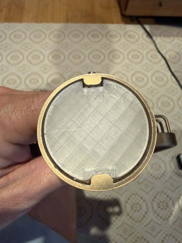 3D-printed puck test-fit inside the brass escutcheon, showing visible print layer lines